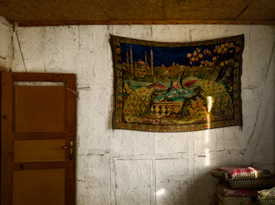 A cozy living room wall adorned with a large fabric wall tapestry featuring intricate vintage patterns.