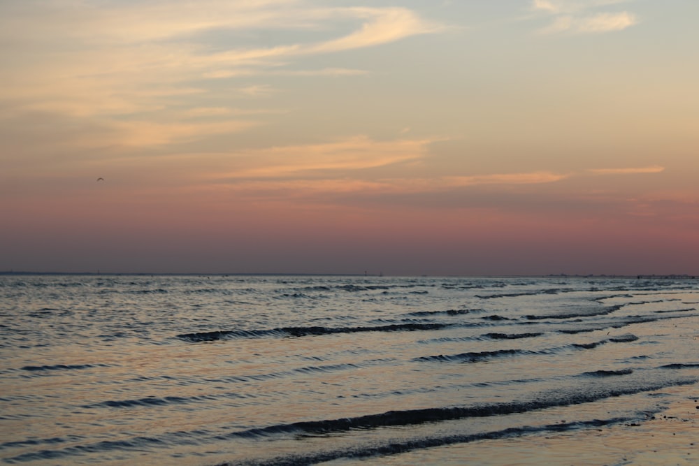 a beach with waves and a sunset