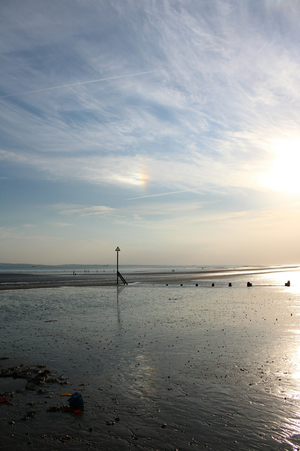 a beach with a pole and a body of water with people on it