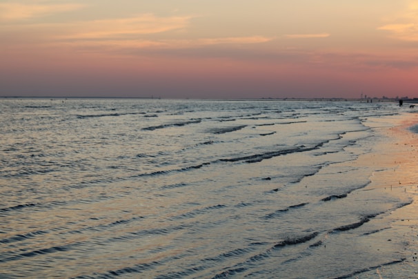A peaceful beach scene with gentle waves and a colorful sky.