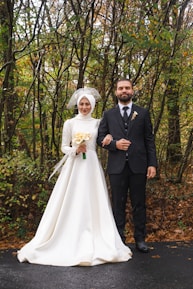 A couple dressed in wedding attire standing together in a lush forest surrounded by flowers.