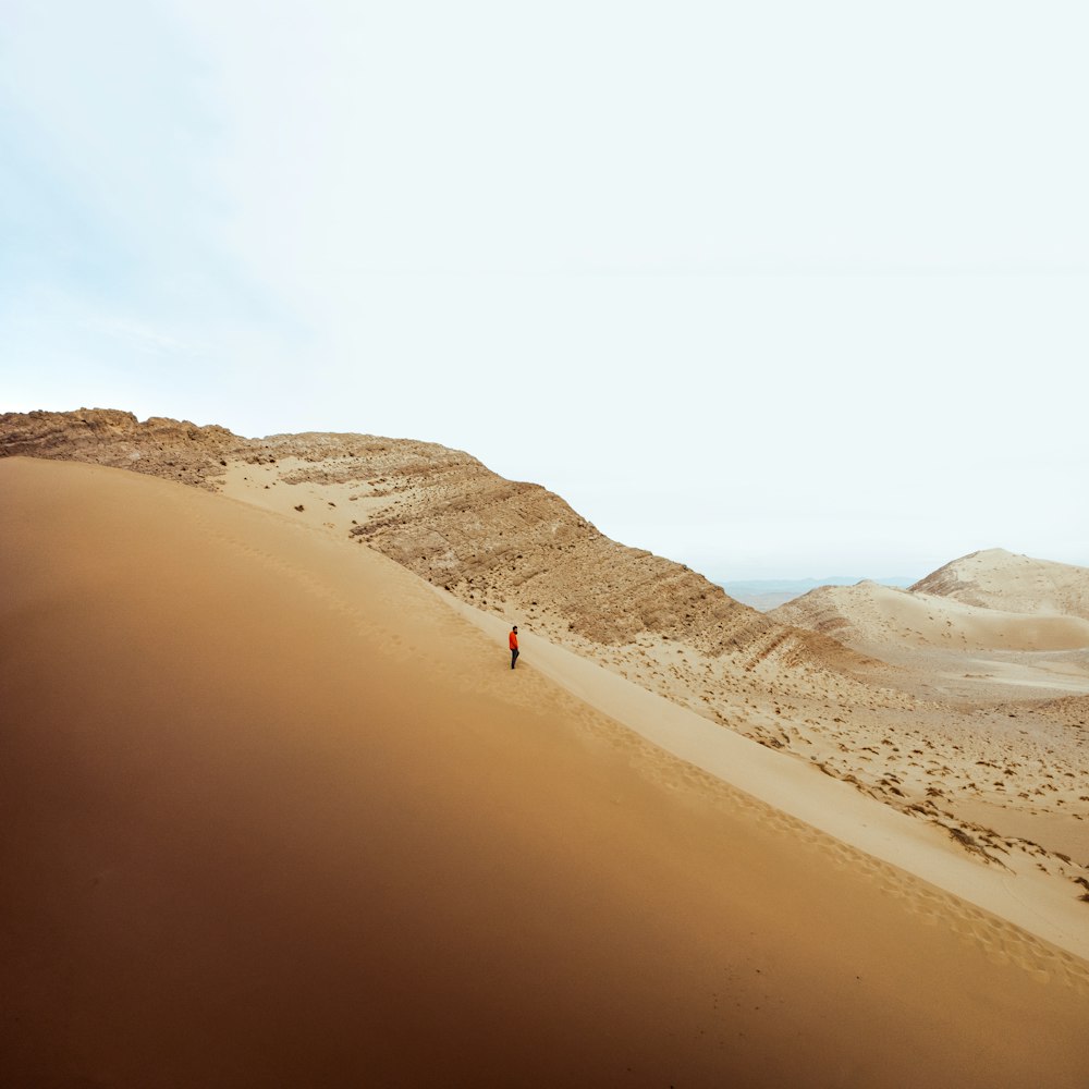 uma pessoa andando em uma colina de areia