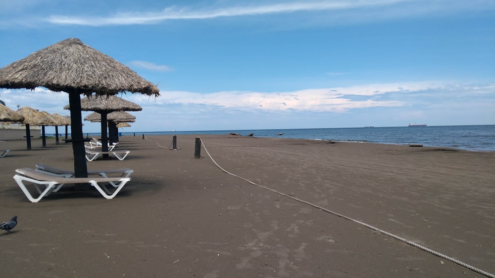 uma praia com um guarda-sol de palha e cadeiras