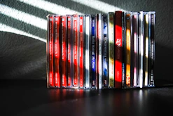 Stack of CDs showing both French and English versions side by side on a rustic wooden table.