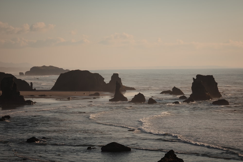 a rocky beach with a body of water in the background