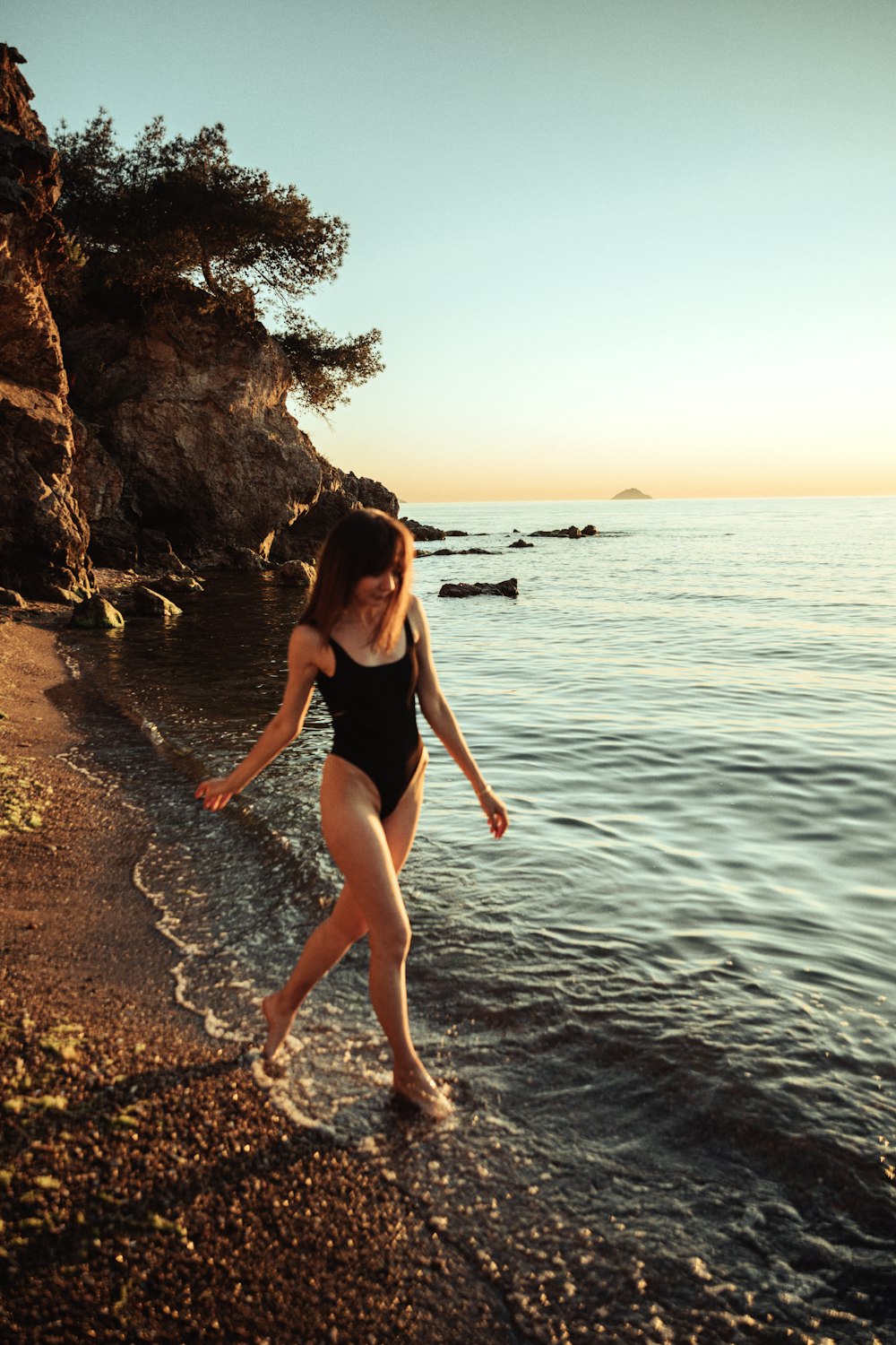 a woman in a swimsuit on a beach by the water