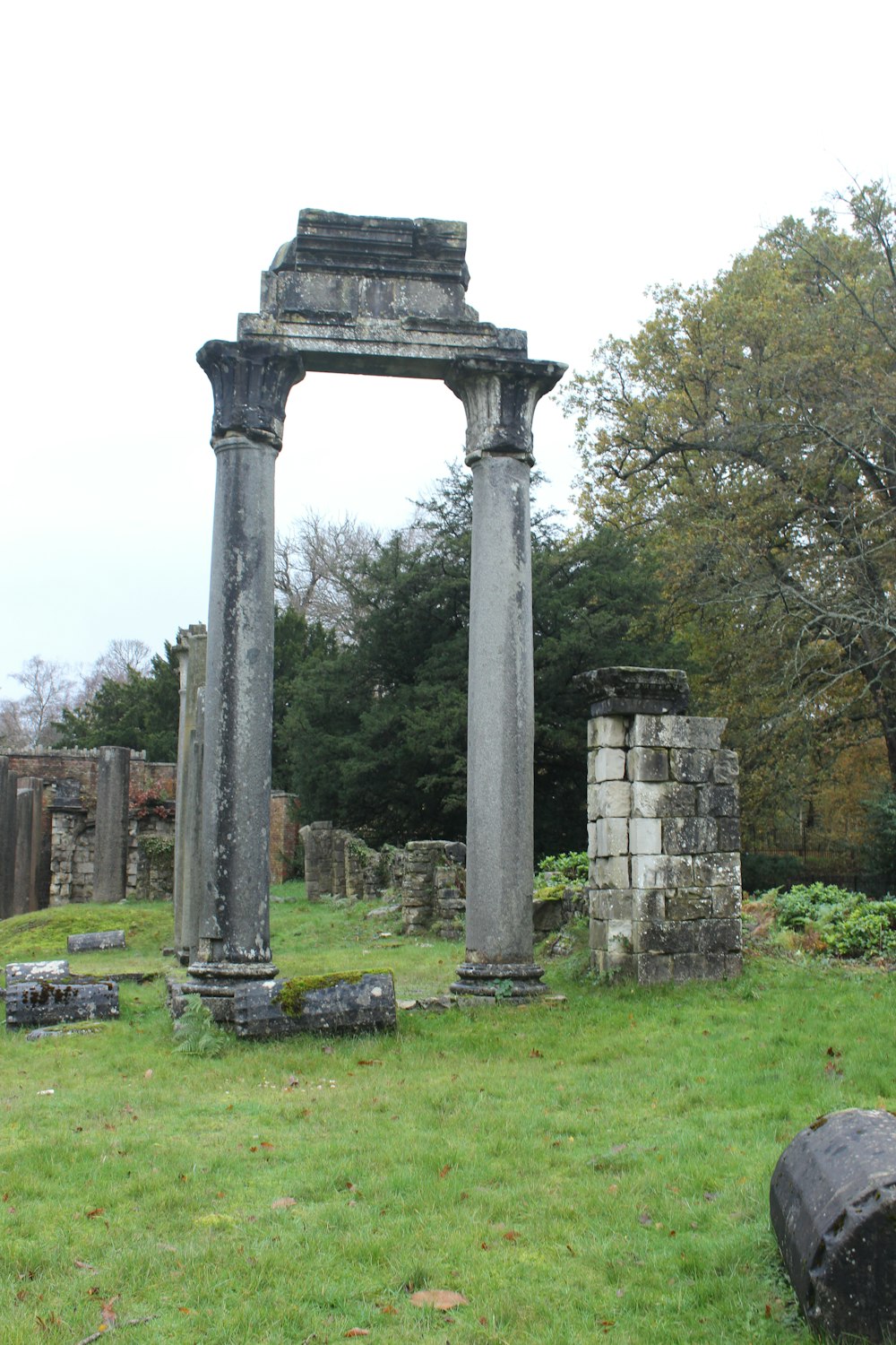 a stone arch with columns in a grassy area