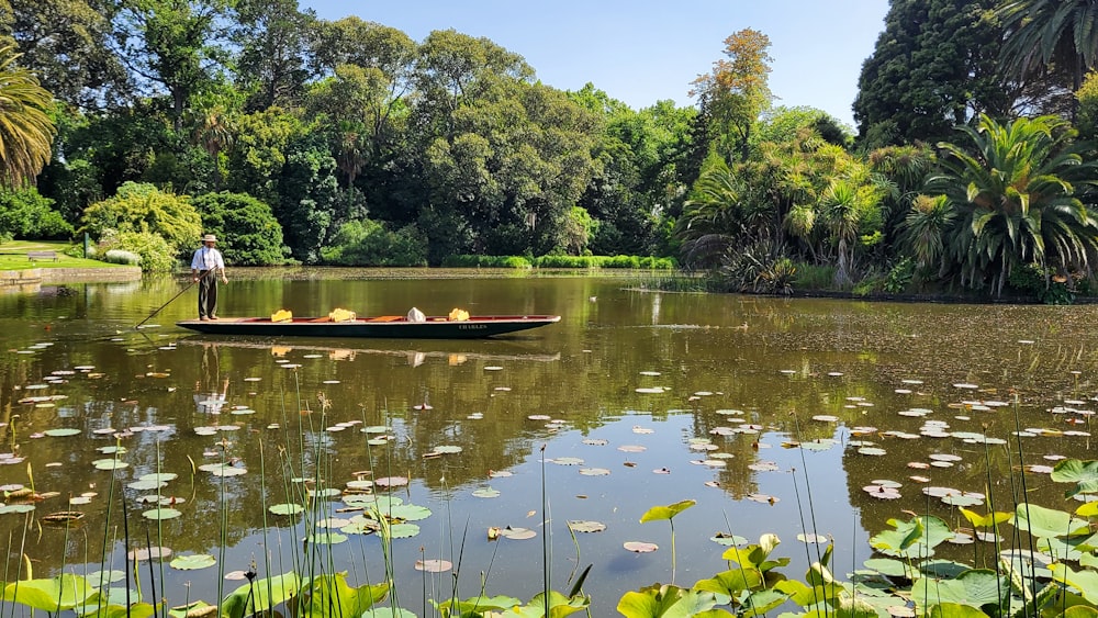 a person standing on a boat in a pond