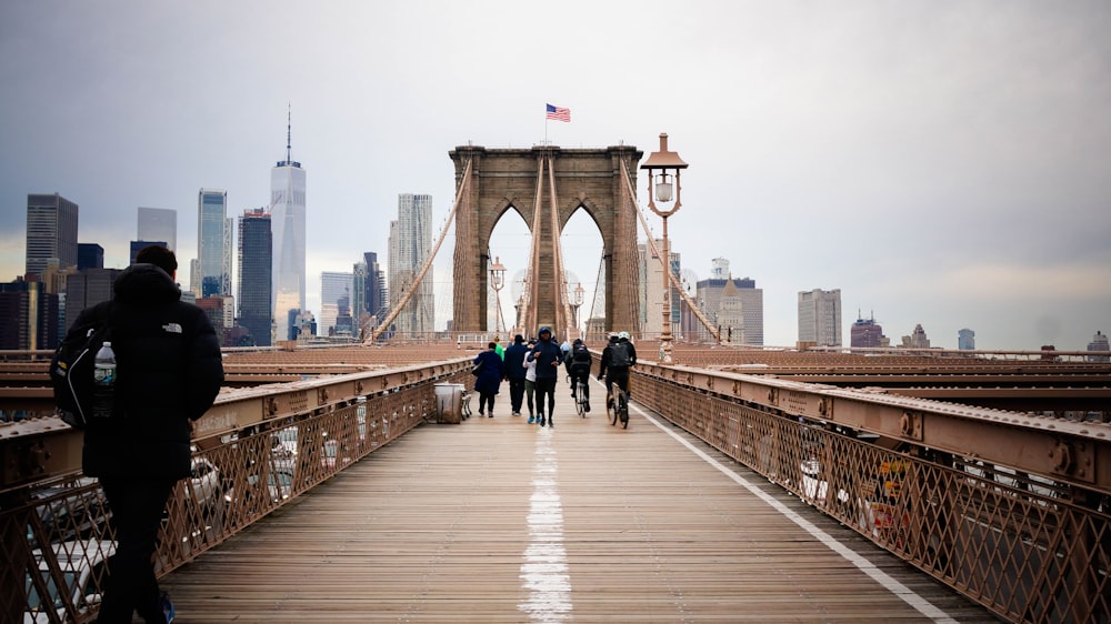 a group of people walking on Brooklyn Bridge with a city in the background