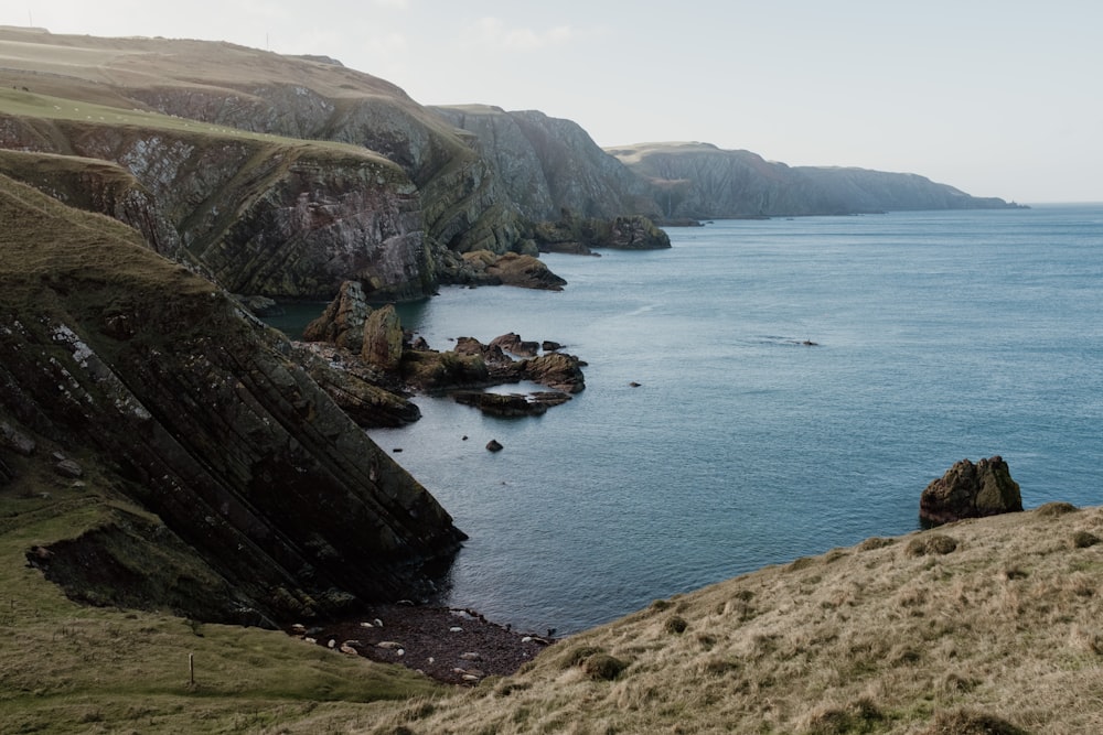 a rocky beach with a body of water in the background