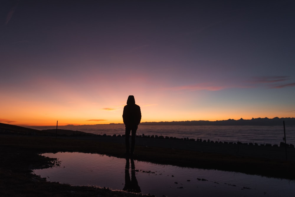 a person standing in a body of water with a sunset in the background