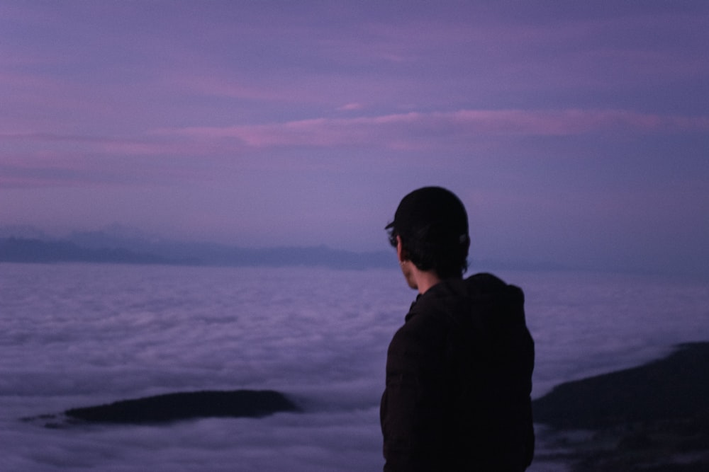 a man standing on a cliff looking at the water