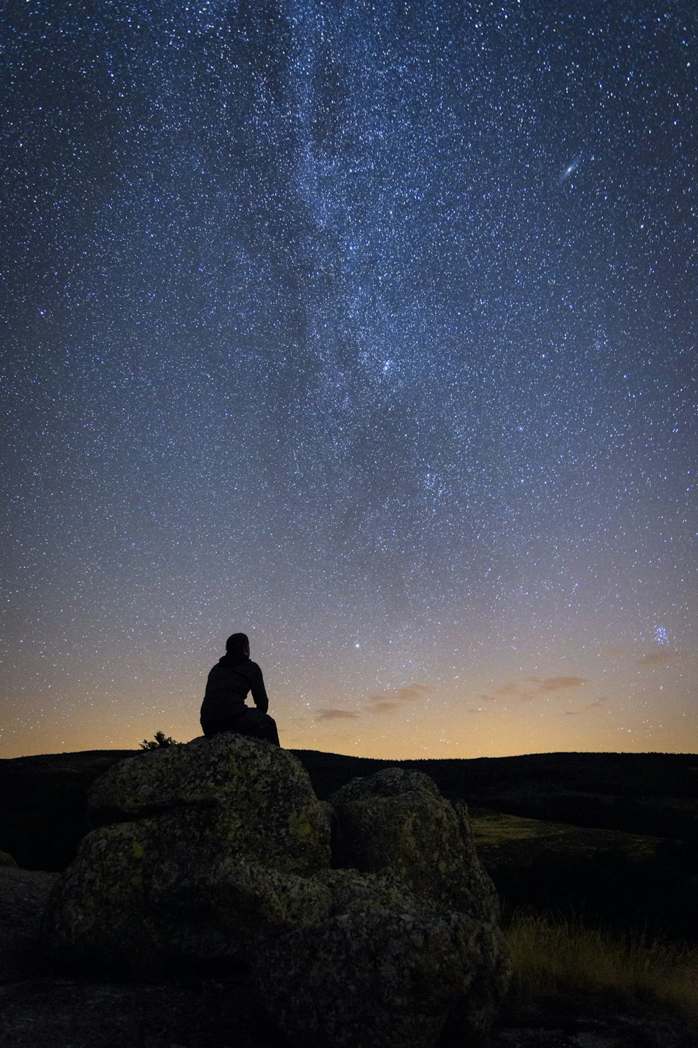 a person sitting on a rock looking at the stars in the sky