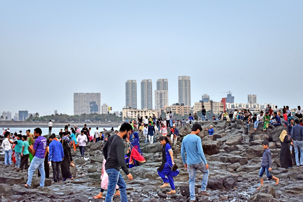 a group of people standing on a rocky area with a city in the background