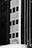 A black-and-white image depicts a high-rise building with a grid-like pattern of windows. A person wearing a harness and work gear is standing on a ledge, seemingly involved in maintenance or cleaning activity on the facade.