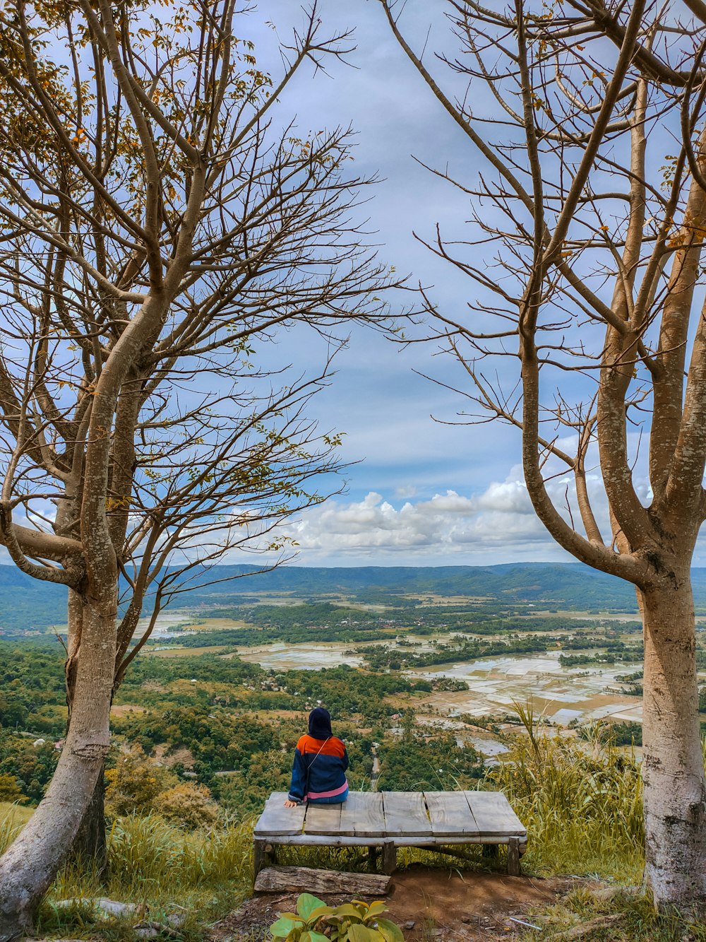 une personne assise sur un banc surplombant une vallée