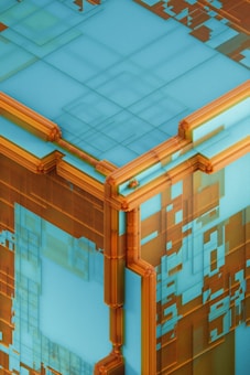 A geometric abstract image featuring a large, cube-like structure. The cube has a complex surface with layered, semi-transparent orange and turquoise elements creating a grid-like pattern. The design gives a futuristic and digital feel with sharp lines and intricate details.