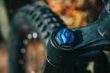 Close-up of a bicycle suspension fork showing a blue adjustment knob labeled 'FLOAT' and 'AIR'. The bike's fat tire and frame are visible in the background.