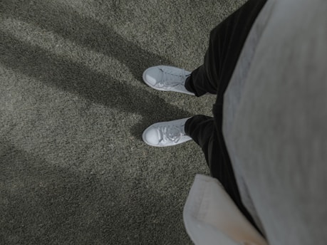 a person wearing white shoes standing on a carpet