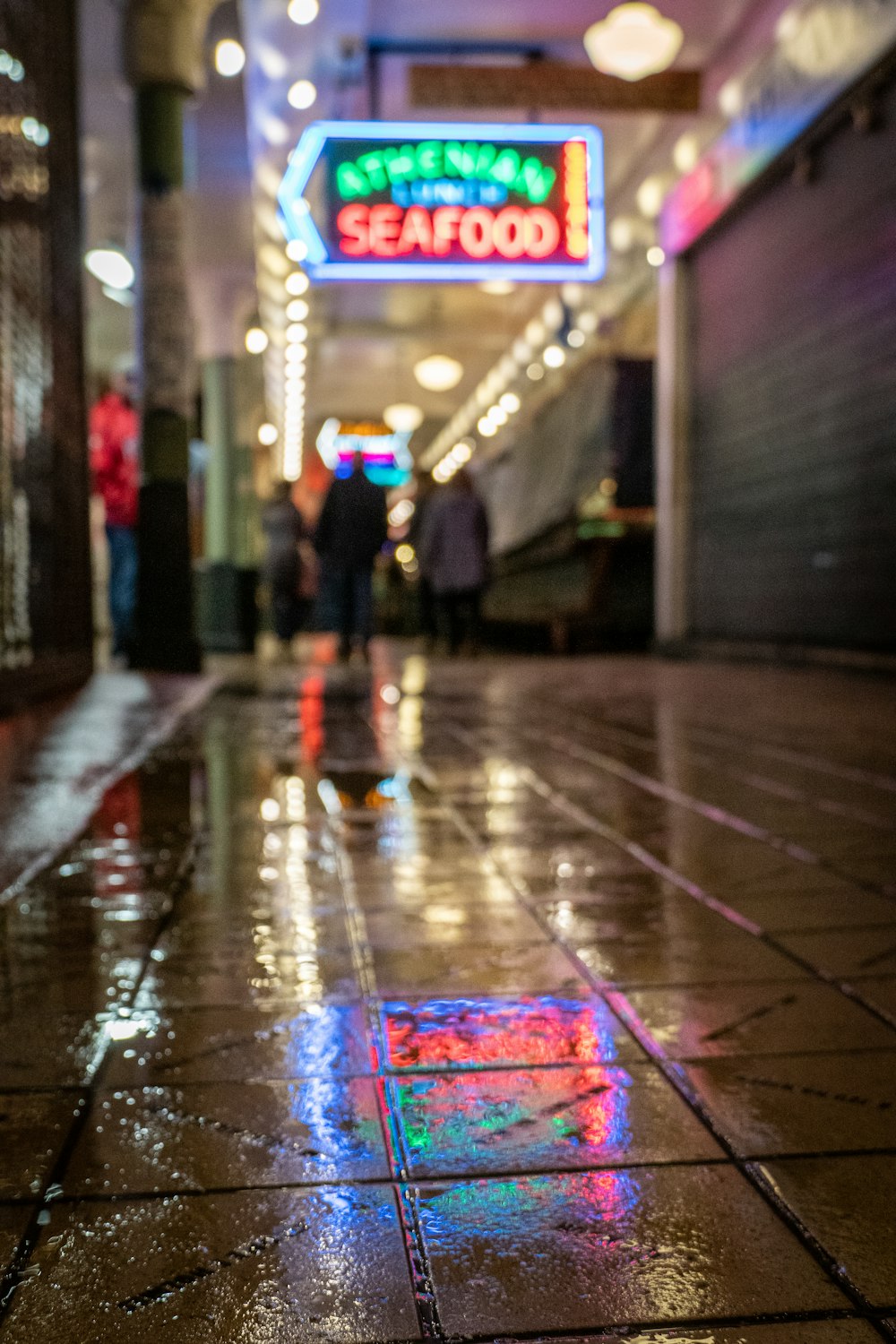 a group of people walking in a street with a neon sign