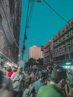 A bustling urban street scene with diverse people engaged in daily activities under clear skies.