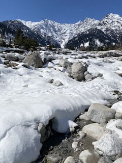 a rocky area with snow and mountains in the background