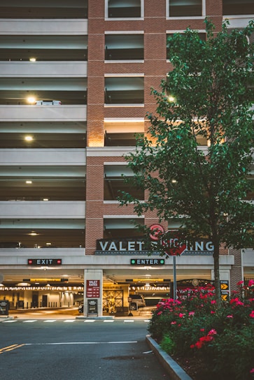 A valet attendant in uniform assisting a guest with their vehicle outside a hotel entrance.