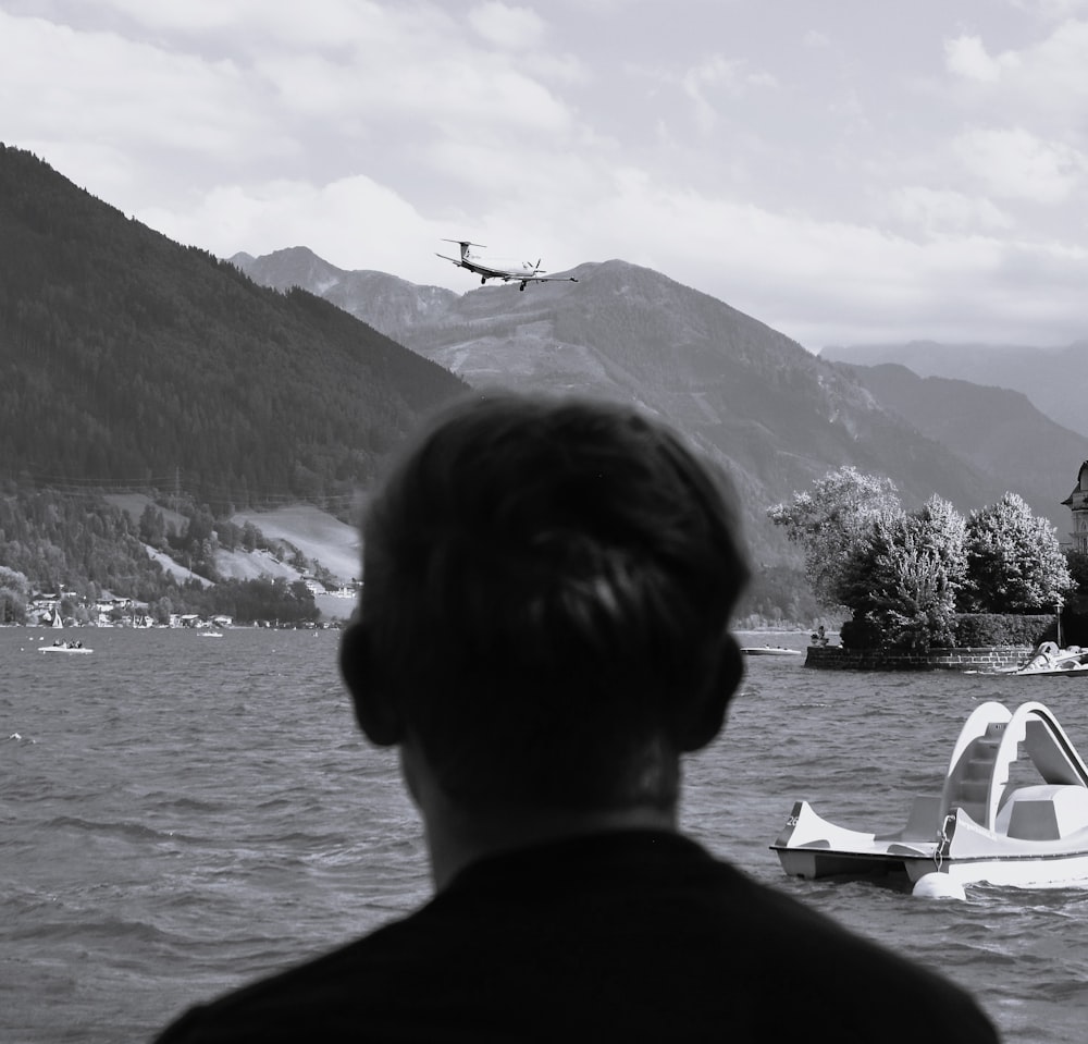 a man looking at a plane flying over a lake