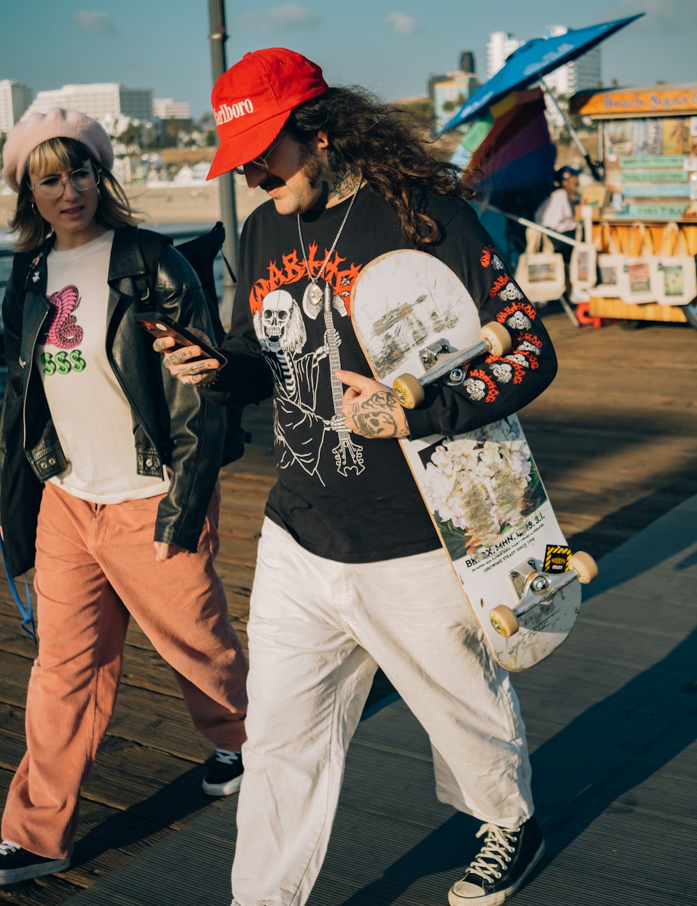 a couple of people walk with a skateboard