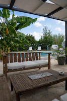 Cozy outdoor seating area beside a villa pool surrounded by lush greenery.