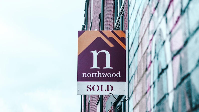 A real estate for sale sign, representing shifting national asking prices and price cuts on listings