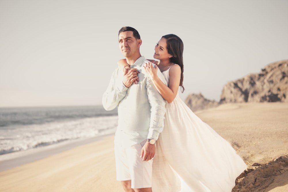 a man and woman posing on a beach