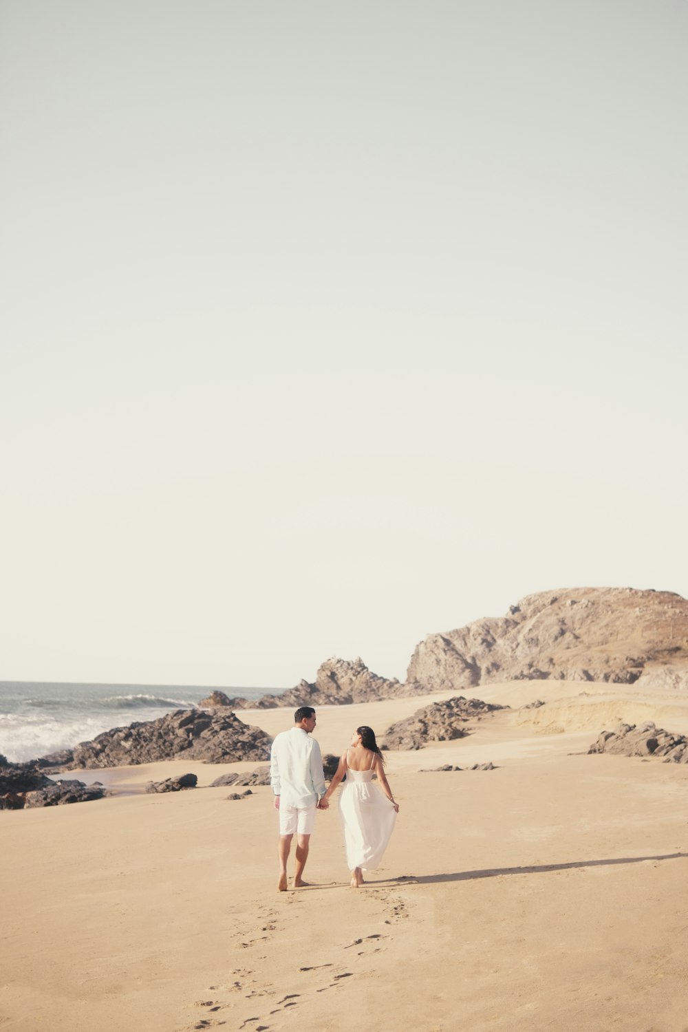 um homem e uma mulher que caminham em uma praia