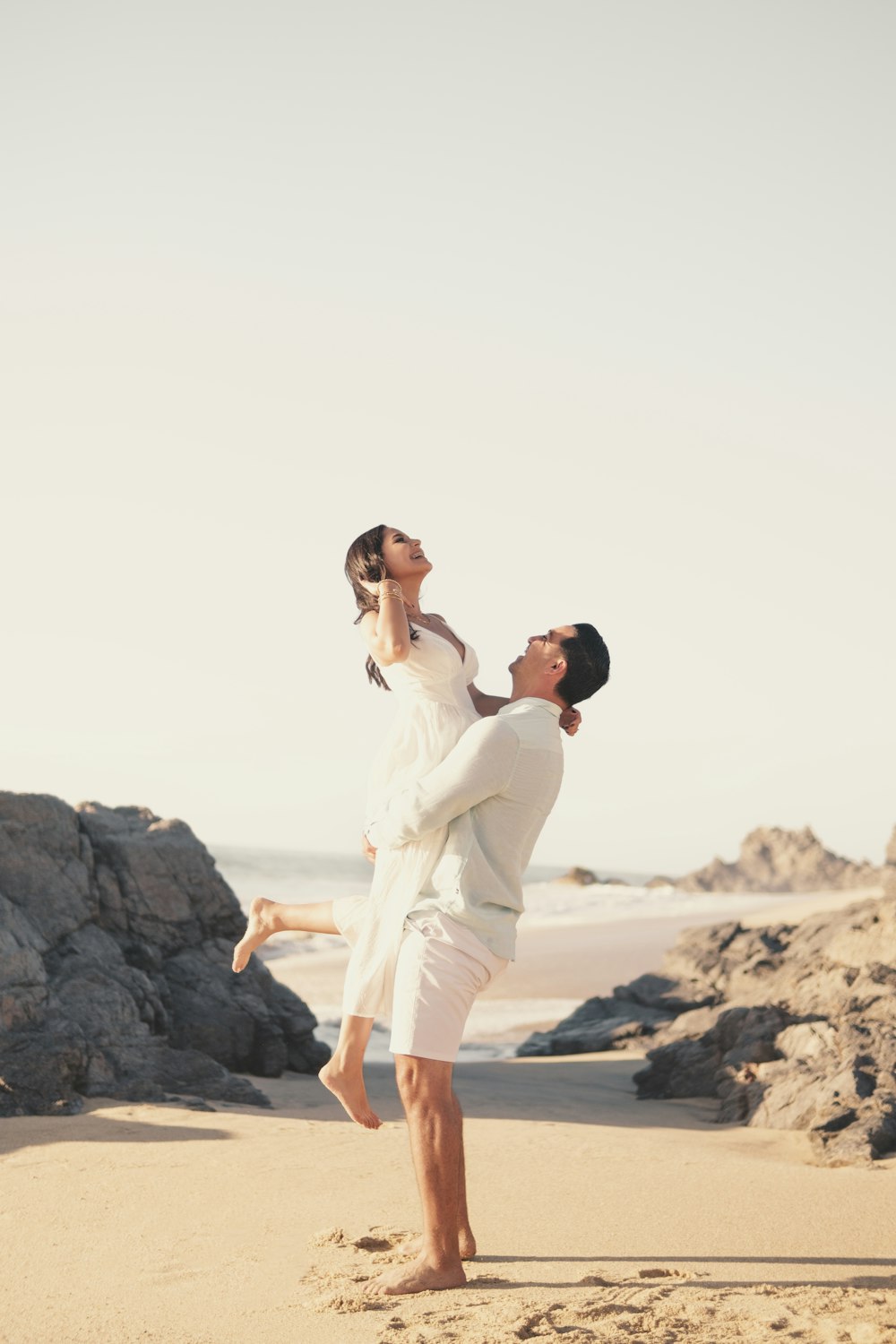 a man and woman holding each other on a beach