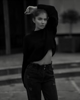 A casual-chic look featuring a lightweight knit sweater in muted sage green, styled with high-waisted jeans outdoors.