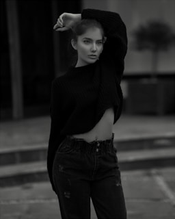 A model wearing a dark brown sweater in a park during fall.