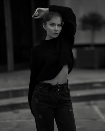 A model wearing a cozy, stylish sweater paired with sleek jeans, standing against a soft urban backdrop.