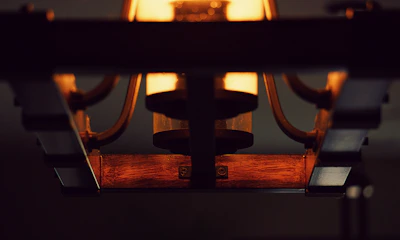 Close-up of a handcrafted wooden lamp with metal accents glowing warmly in a cozy room.
