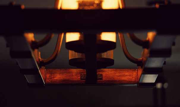 Close-up of intricate wooden details on a Luzara lamp with soft light shining through