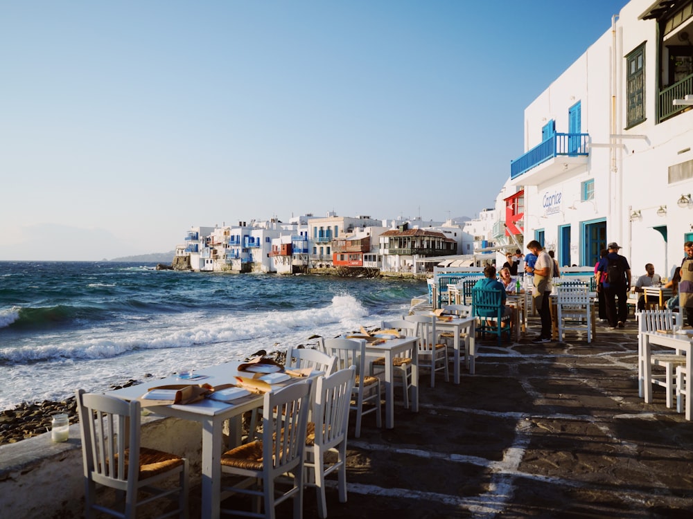 a group of tables and chairs next to a body of water