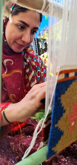 Artisan Moroccan woman weaving a traditional rug in a sunlit workshop.