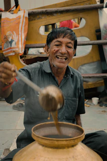 Smiling hands pouring golden ghee onto a warm chapati on a wooden plate