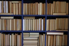 A neat bookshelf filled with university press publications in blue and white covers.
