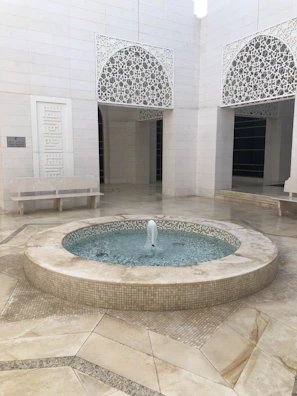 A peaceful courtyard of a Berlin mosque with green plants and a small fountain.