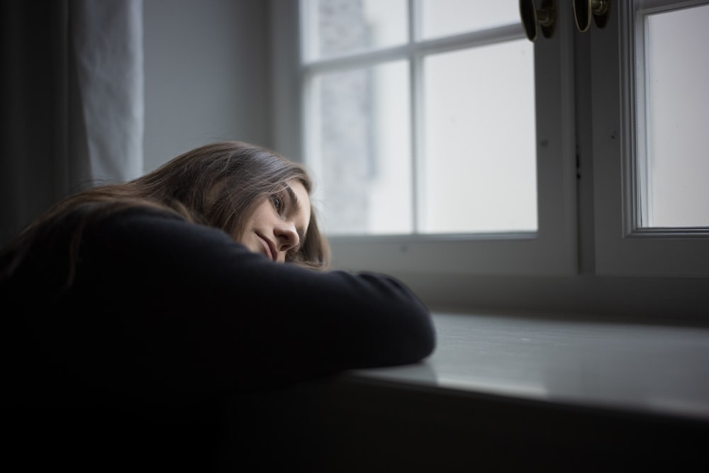 a woman leaning against a window