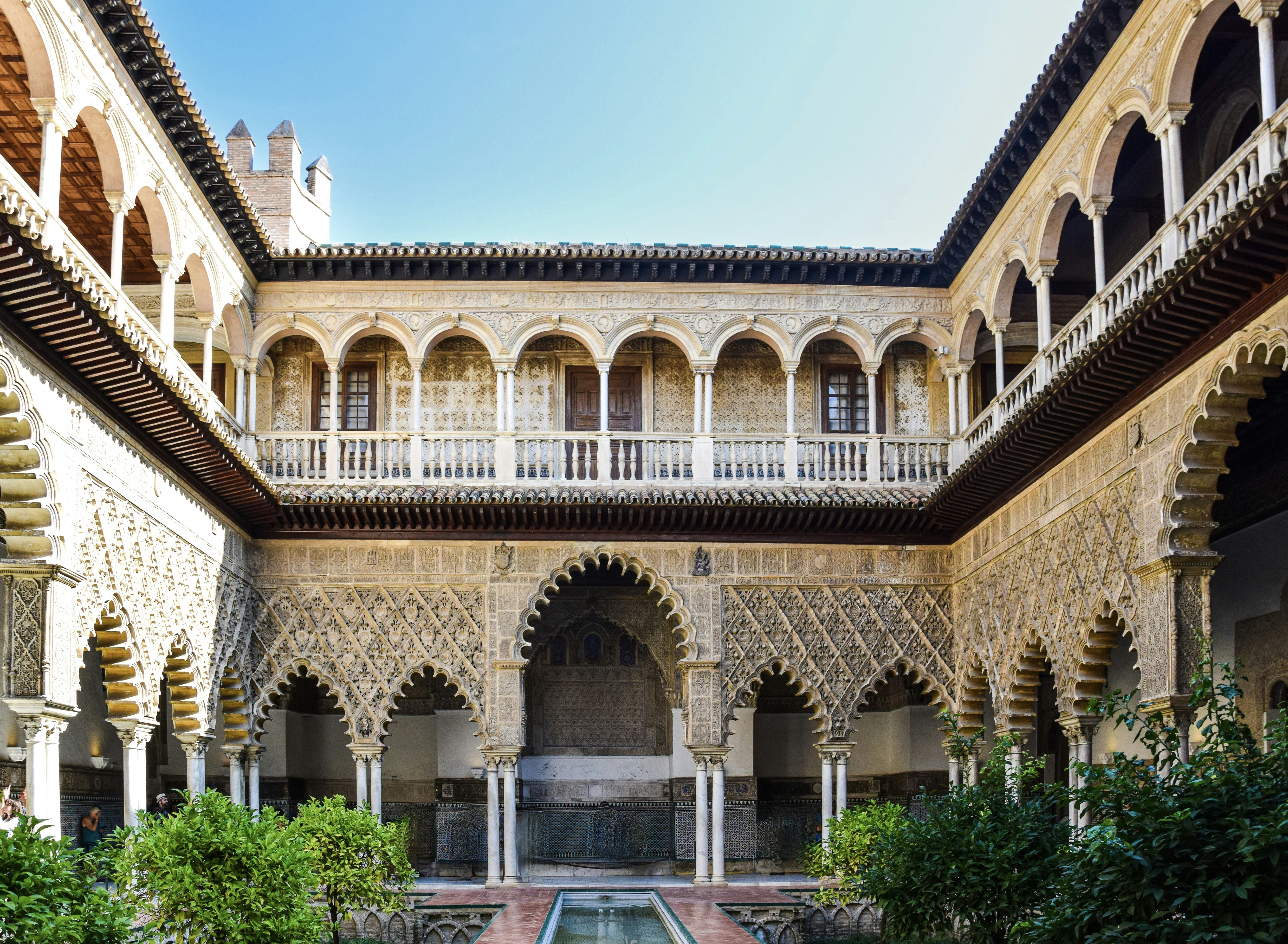 a large building with a courtyard with Alcázar of Seville in the background