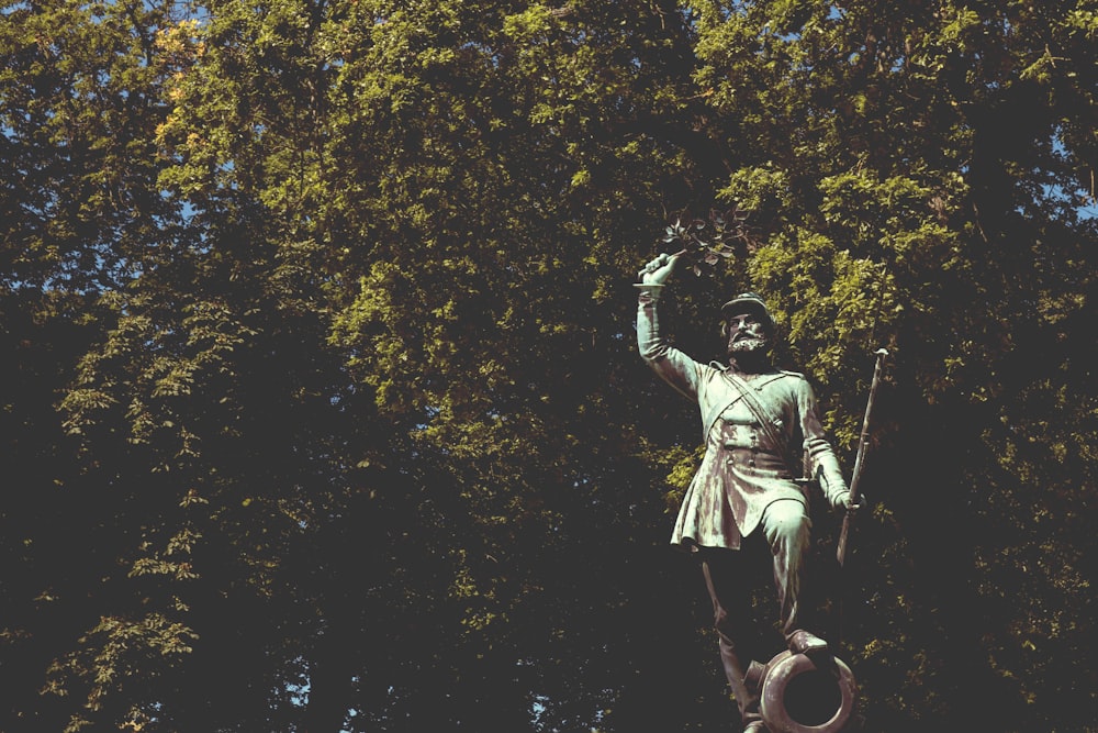 a statue of a man holding a sword in a forest