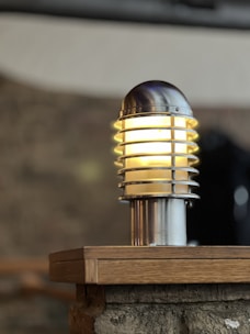 A sturdy metal hanging garden lantern glowing warmly beside a heavy-duty umbrella base.