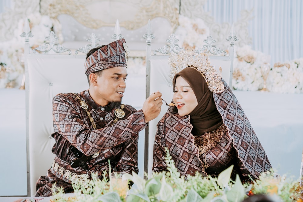 a man and woman sitting in a field of flowers