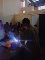 Group of students attentively observing welding process in a well-equipped classroom.